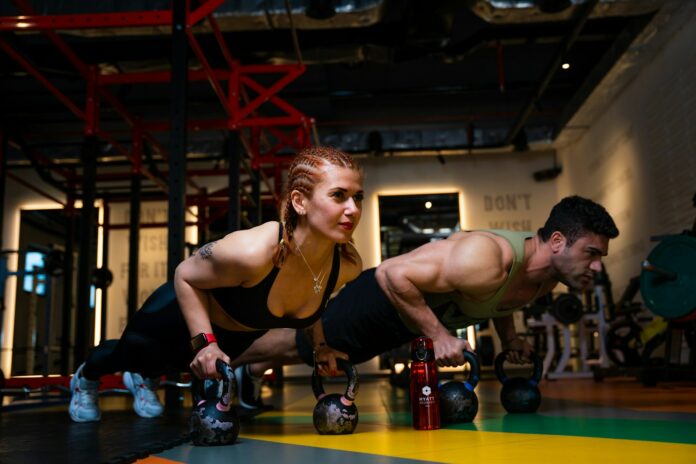 Photo by Akram Huseyn a man and a woman doing push ups with dumbbells