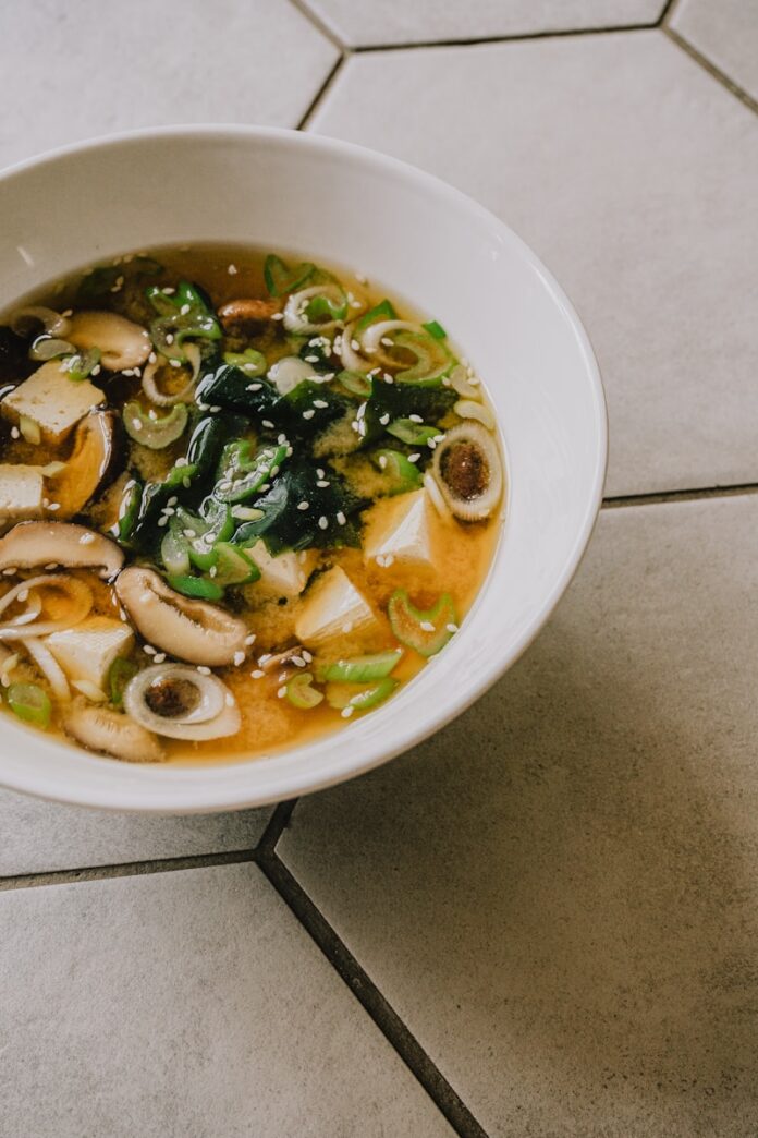 Photo by Fernando Lavin a white bowl filled with soup on top of a tiled floor
