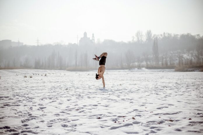 Photo by Alisher Gubaidullin woman in black tank top and brown shorts jumping on snow covered ground during daytime