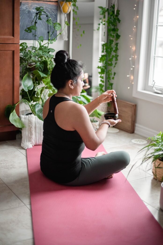 Photo by Shashi Chaturvedula a woman sitting on a pink mat