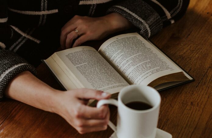 A person sitting on the floor with a book and a cup of coffee