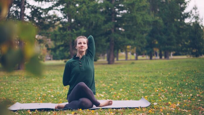 Woman practicing yoga on mat in park