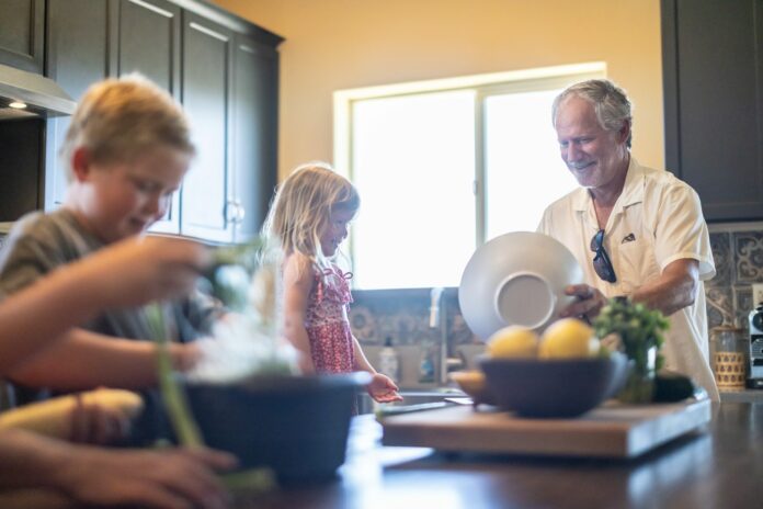 Grandfather and grandchildren prepare food in kitchen
