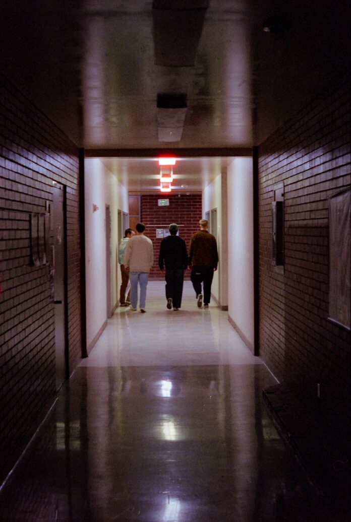 People walk down a dark, brick-walled hallway.